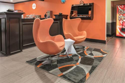 a lobby with three orange chairs in a waiting room at Howard Johnson by Wyndham Near Schlitterbahn in New Braunfels