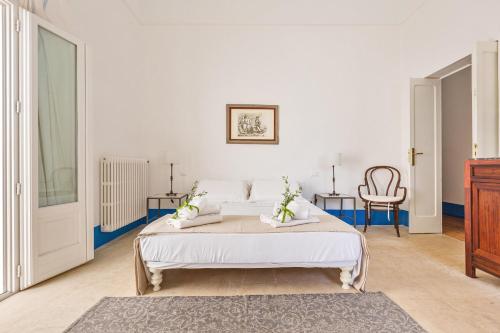 a white bedroom with a bed and a chair at Dimora Blu by BarbarHouse in Cerfignano