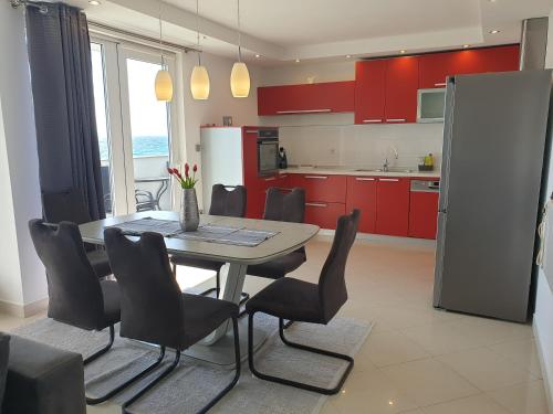 eine Küche mit roten Schränken sowie einem Tisch und Stühlen in der Unterkunft Apartment Hajdi in Podstrana