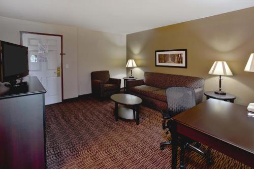 a hotel room with a couch and a table and a tv at AmericInn by Wyndham Beaver Dam in Beaver Dam