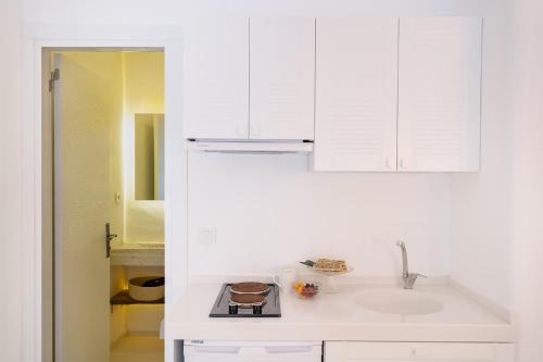 una cocina con armarios blancos y fregadero en Yasos Suites, en Cesme
