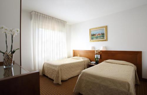 a hotel room with two beds and a vase with flowers at Hotel Villa Delle Rose in Pescia