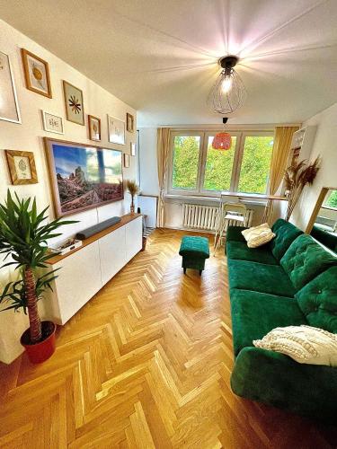 a living room with a green couch and wooden floors at Luxurious BOHO style apartm. *HOME OFFICE* +Desk in Katowice