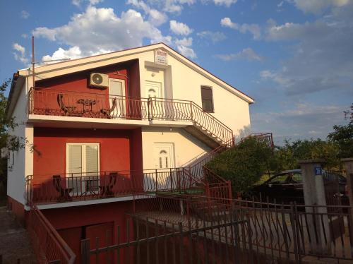 a white and red building with a balcony at Airport home Radinovic in Podgorica