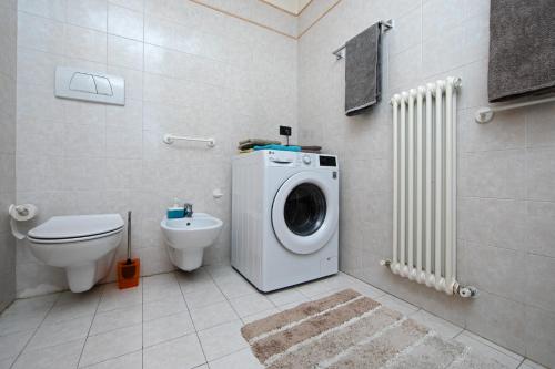 a bathroom with a washing machine and a toilet at Hike & Bike Home Helena in Arco