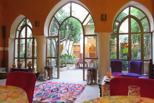 a room with arched windows and tables and chairs at Riad Jnane d'Ô in Marrakech