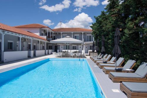 a swimming pool with chairs and umbrellas next to a building at Philoxenia Suites in Nea Vrasna