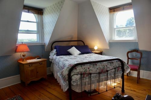 a bedroom with a bed and a chair and two windows at The New Glasgow Inn in New Glasgow