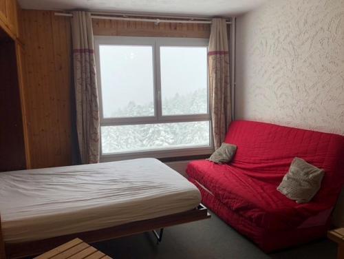 a bedroom with a red bed and a window at studio tout confort au pied des pistes du lioran in Laveissière