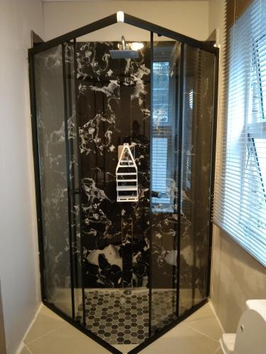 a shower with a black and white wall at Menlyn Mews Guesthouse in Pretoria
