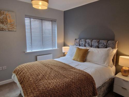諾里奇的住宿－Norwich, Lavender House, 3 Bedroom House, Private Parking and Garden，一间卧室配有一张床、两盏灯和一个窗户。