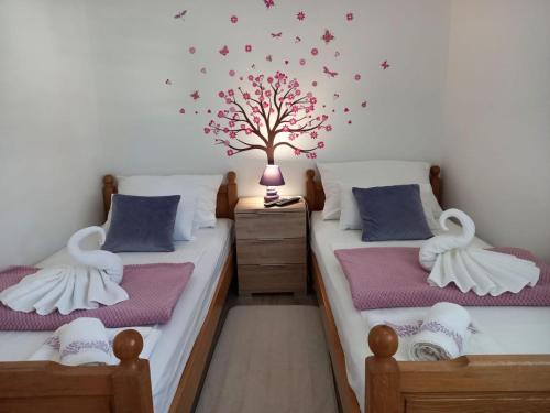 2 camas en una habitación con un árbol en la pared en Villa Nora, en Pisak