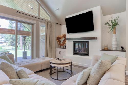 a living room with white furniture and a flat screen tv at Merganser Memories in Sunriver