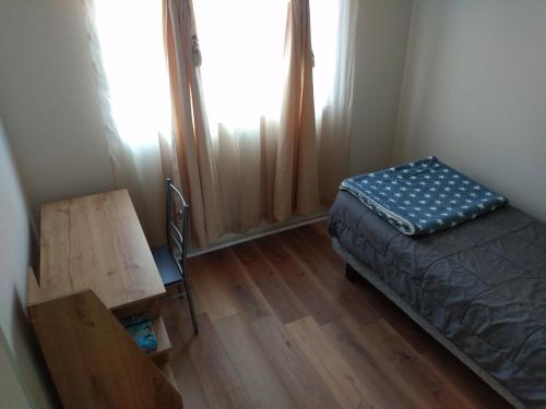 a bedroom with a bed and a desk and a window at Casa La Florida in La Serena