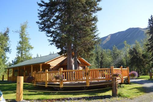 a log cabin with a porch and a tree at Summit Lake Lodge in Summit Lake