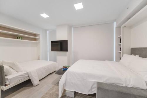 biała sypialnia z 2 łóżkami i telewizorem w obiekcie Wonderful Studio Apartment with Great Views and Pool w Miami