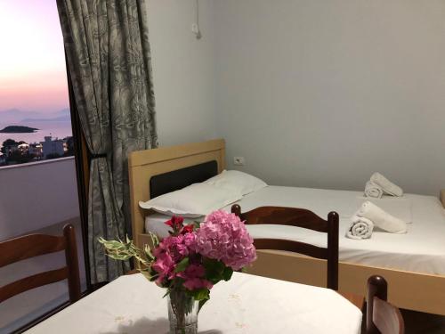 a room with two beds and a vase of flowers on a table at Vila Jeti in Ksamil
