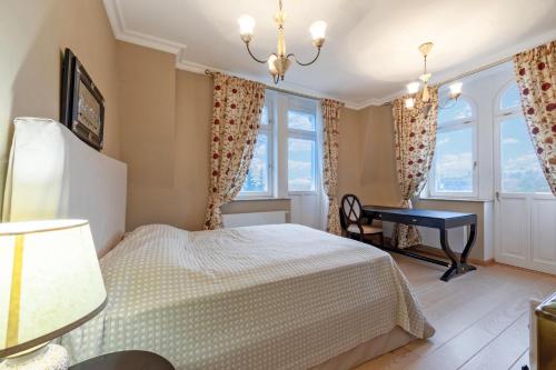 a bedroom with a bed and a desk and windows at Luxury apartment Diamond in Karlovy Vary