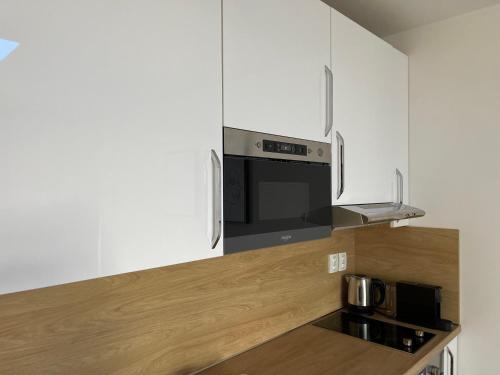 a kitchen with white cabinets and a black microwave at ne-doma in Chomutov