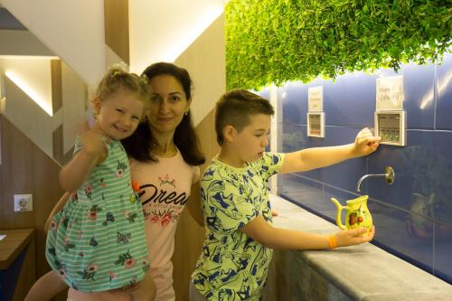 a woman and two children standing at a bathroom counter at Truskavets 365 Hotel in Truskavets