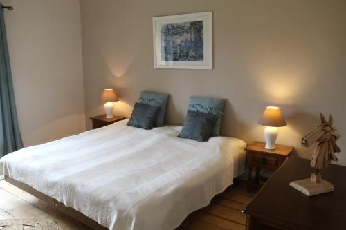 a bedroom with a large white bed with two lamps at Manoir du Taillis in Heugon