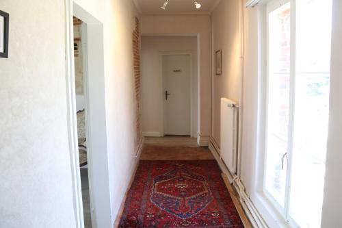 a hallway with a red rug on the floor and a door at Manoir du Taillis in Heugon