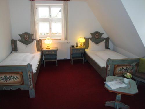 two beds in a room with two tables and a window at Hotel Haus Appelberg in Dinkelsbühl