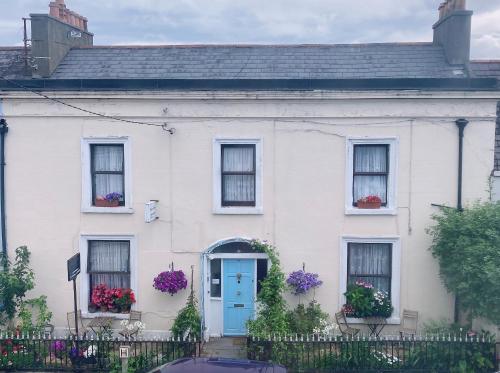 een wit huis met een blauwe deur en ramen bij Mulgrave Lodge in Dun Laoghaire