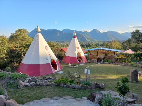 two umbrellas in a yard with a house at Biosfera Lodge tipi para 3 personas in Oxapampa