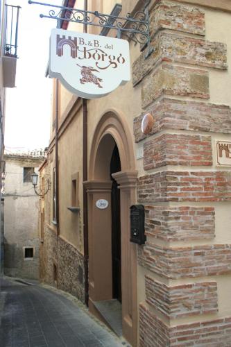 a sign on the side of a building with a door at B&B Del Borgo in San Marco Argentano