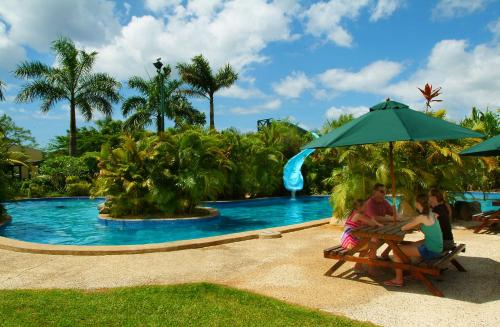 a group of people sitting at a table by a pool at Grand West Villas in Nadi