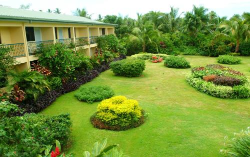 a yard with bushes and flowers in front of a building at Grand West Villas in Nadi
