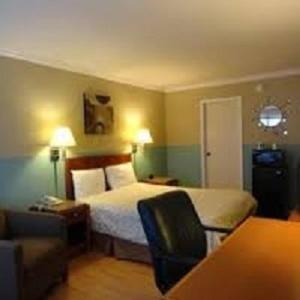 Sequoia Inn Redwood City في ريدوود سيتي: غرفه فندقيه بسرير واريكه