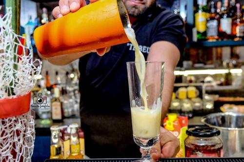 Tebeu coffe and bar في فلوره: رجل يصب الشراب في الزجاج