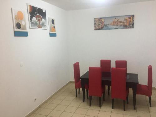 a dining room with a table and red chairs at Appartement Meublé 2 et 3 Chambres Avec Groupe Électrogène À Makèpè in Douala