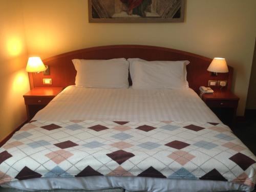 un letto in una camera da letto con due comodini e due lampade di Hotel Piero Della Francesca ad Arezzo