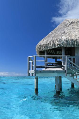 a pier in the water with a thatch roof at Sofitel Kia Ora Moorea Beach Resort in Maharepa