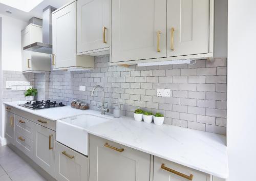 eine weiße Küche mit weißen Schränken und einem Waschbecken in der Unterkunft The Flamingo in London