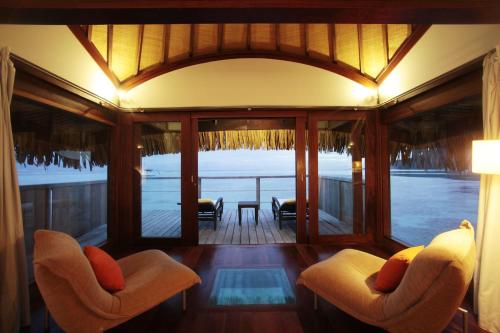 a living room with two chairs and a view of the ocean at Sofitel Kia Ora Moorea Beach Resort in Maharepa