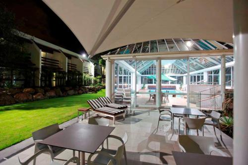 a patio with tables and chairs in a building at Commodore Airport Hotel Christchurch in Christchurch