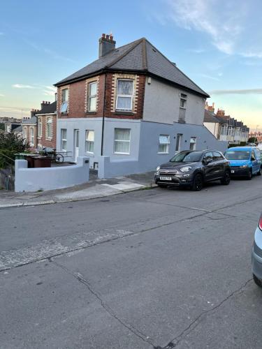 a white house with cars parked in front of it at H &P accommodation in Plymouth