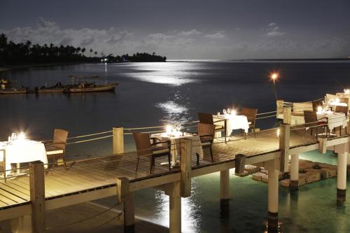 a dock with tables and chairs on the water at night at Sofitel Kia Ora Moorea Beach Resort in Maharepa