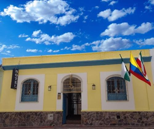 um edifício amarelo com duas bandeiras à frente em Hotel Posada de Santa Elena em Tunja