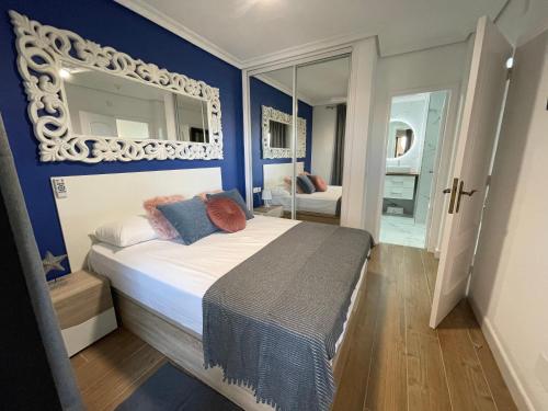 una camera da letto con un letto con pareti blu e uno specchio di Villa Moleiro - Golf del Sur a San Miguel de Abona