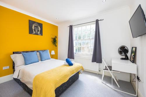 a bedroom with a bed and a yellow wall at Islington Quarter in London