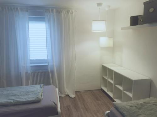 ein weißes Schlafzimmer mit einem Bett und einem Fenster in der Unterkunft Gästehaus, Ferienwohnung, Monteurwohnung, Stedinger Landhotel in Berne