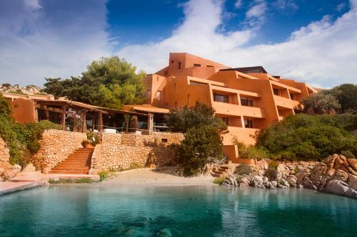 - un bâtiment avec une piscine d'eau en face dans l'établissement Hotel Cala Lunga, à La Maddalena