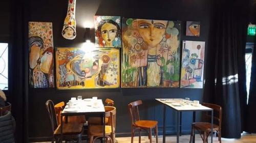 a restaurant with tables and chairs and paintings on the wall at Mousai Hotel Boutique in Capilla del Monte