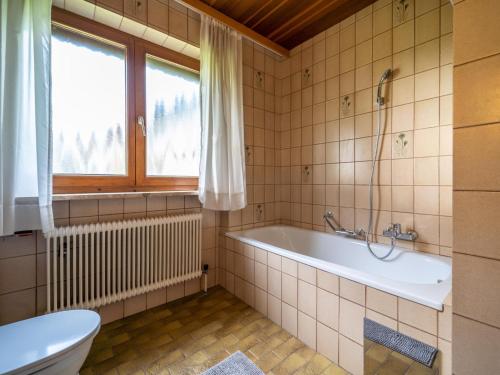 baño con bañera, aseo y ventana en Ferienhaus Schlitters en Fügen