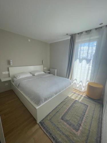 une chambre blanche avec un grand lit et une fenêtre dans l'établissement Charmant logement aux portes de Paris - STADE DE FRANCE - 12 min à pied, à Saint-Denis